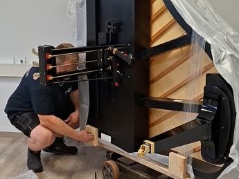 Der Klaviertransporteur entfernt die Schrauben am Flügel Transportschlitten in der Piano Academy Oberkirch
