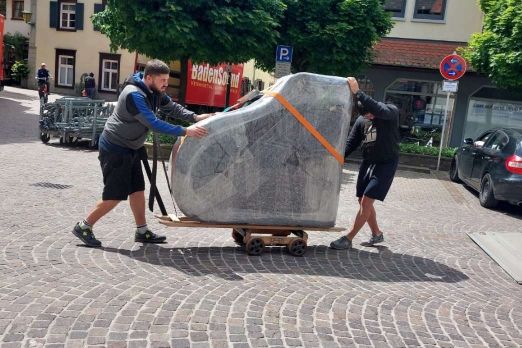 Der Flügel macht sich von Piano Fies aus mit den zwei Fachtransporteuren auf den Weg und wird auf dem Rollwagen in Oberkirch über Kopfsteinpflaster gerollt