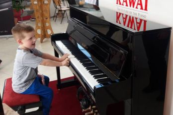Ein Kind spielt Klavier auf einem Mietklavier