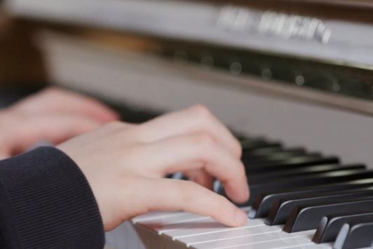 Kinderhände auf einer Klavier Tastatur von Wilh. Steinberg