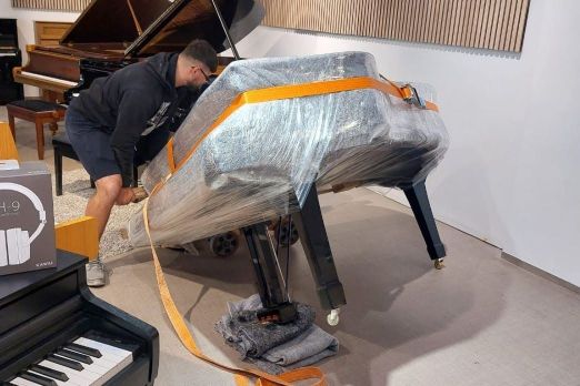Der verkaufte Flügel wird nach dem Verpacken zum Transport inm Piano Fies Ausstellungsraum in Oberkirch auf den Rollwagen gekippt.