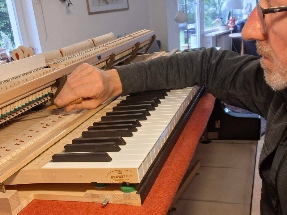 Klavierbaumeister Robert Fies stellt die Steighöhe einer Flügelmechanik im Rahmen einer Flügelreparatur in Baden-Baden ein