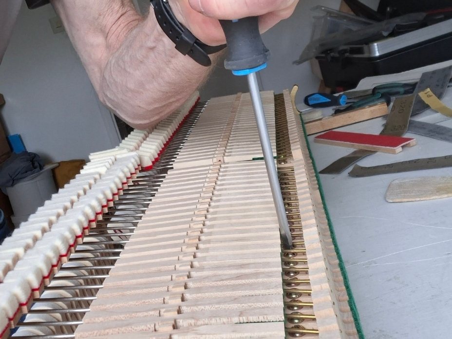 Anziehen von Schrauben an einer Klaviermechanik im Rahmen eines Klavierservice in Kehl