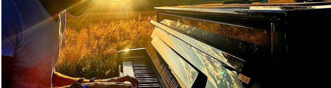 Jemand spielt an einem Kawai Piano im Greien bei Sonnenuntergang